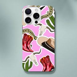 Pink Western iPhone case featuring red cowboy boots, green cactus, horseshoe, and longhorn skull desert motifs.