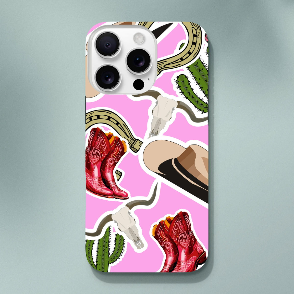 Pink Western iPhone case featuring red cowboy boots, green cactus, horseshoe, and longhorn skull desert motifs.
