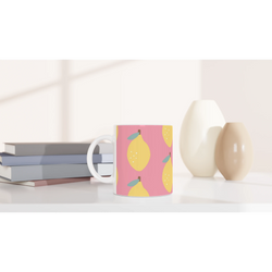 Pink lemon-pattern ceramic mug with yellow lemons and teal leaves, placed on a desk beside books.