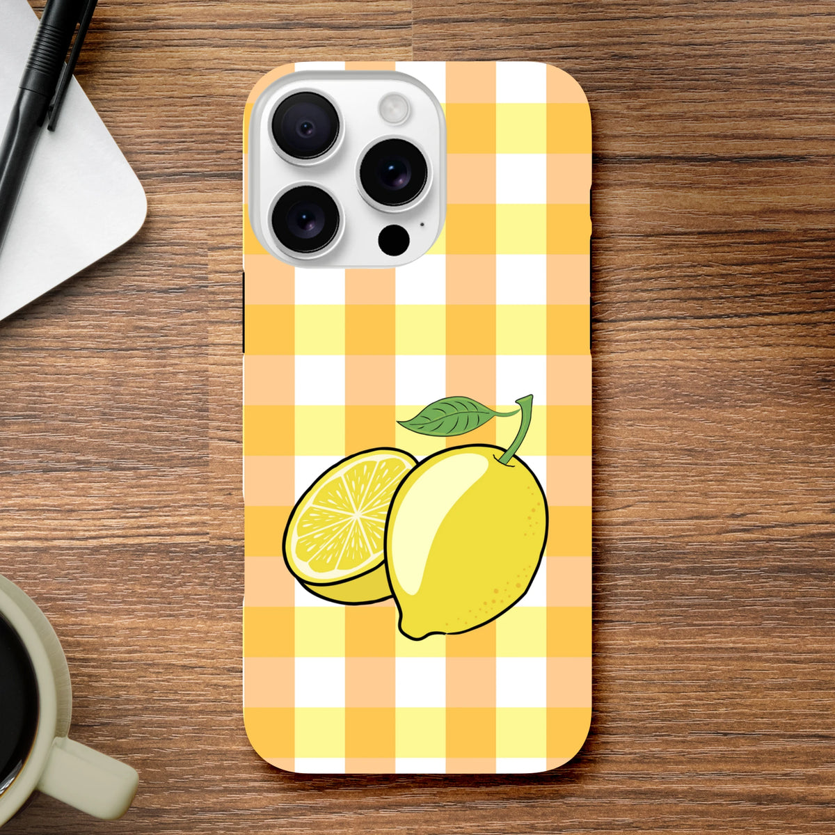 Yellow gingham iPhone case featuring a whole and sliced lemon illustration with green leaf on wooden desk.