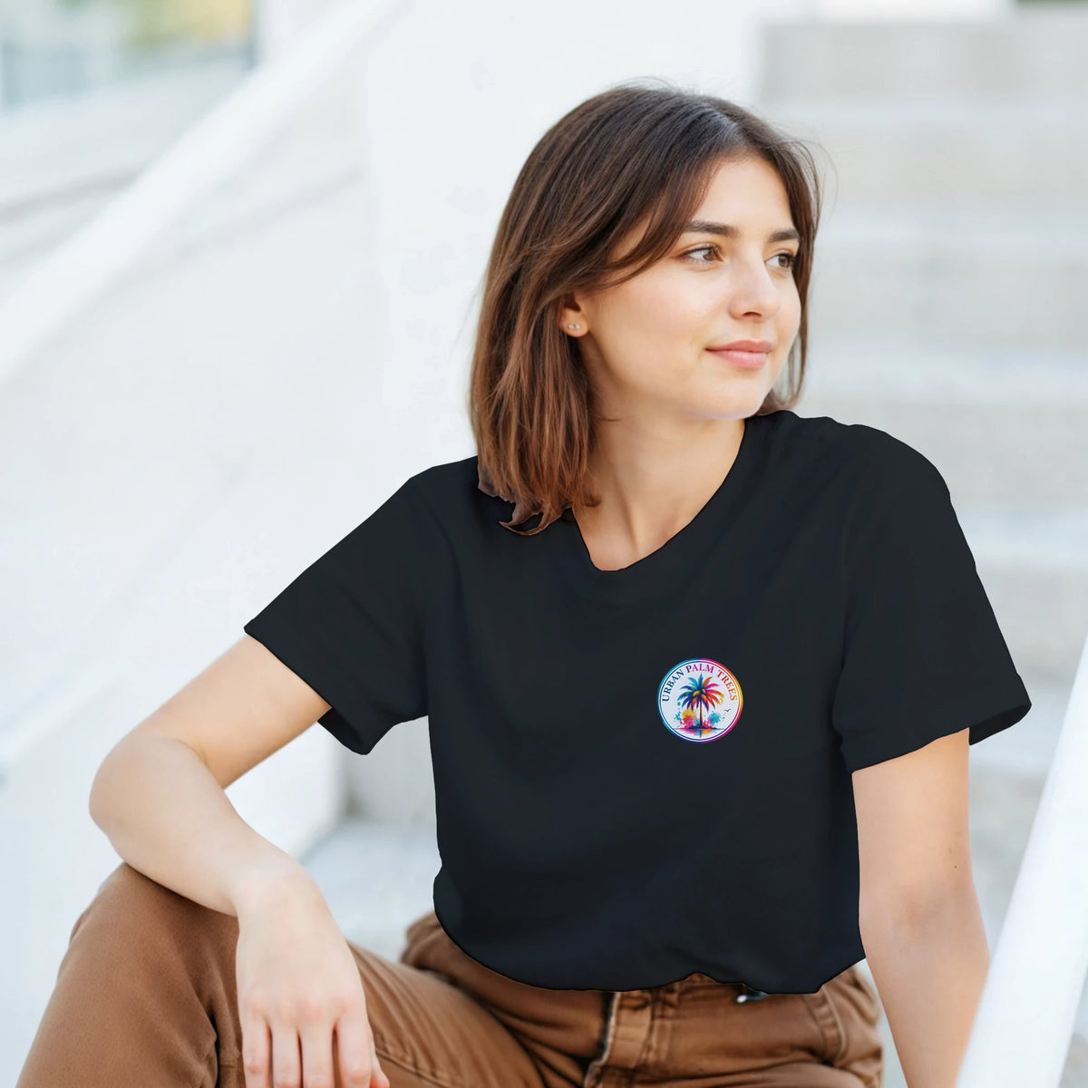 Woman wearing a black retro crop tee with a colorful circular palm tree graphic on the chest and tropical back print design.