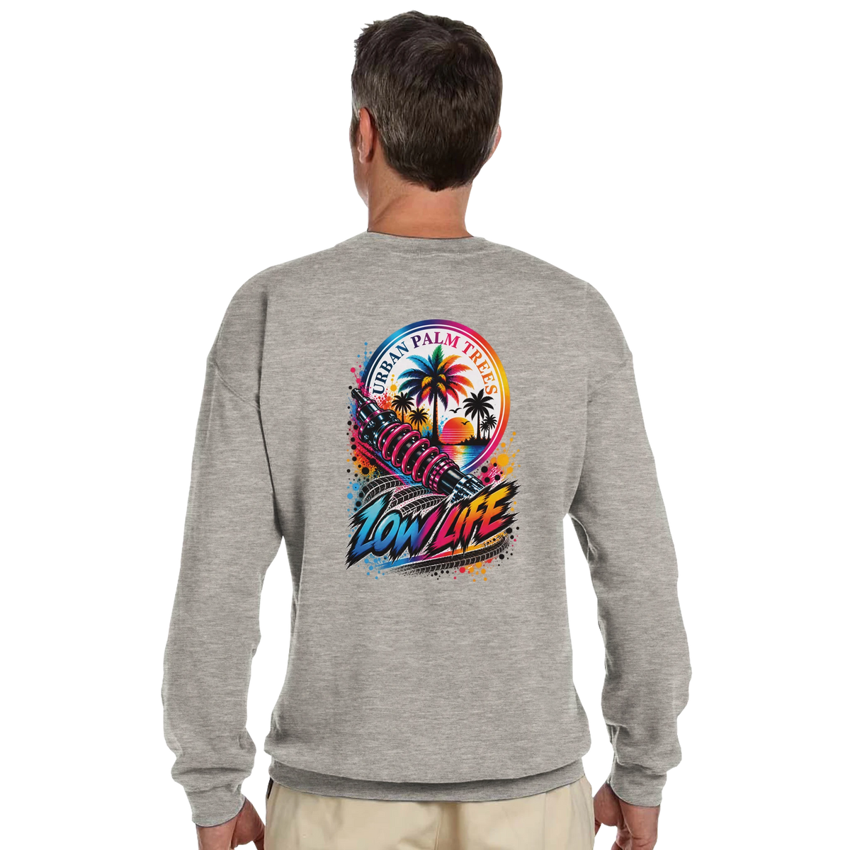 Gray sweatshirt back featuring colorful "Low Life" graphic with shock absorber, palm trees, and sunset for modified car culture.