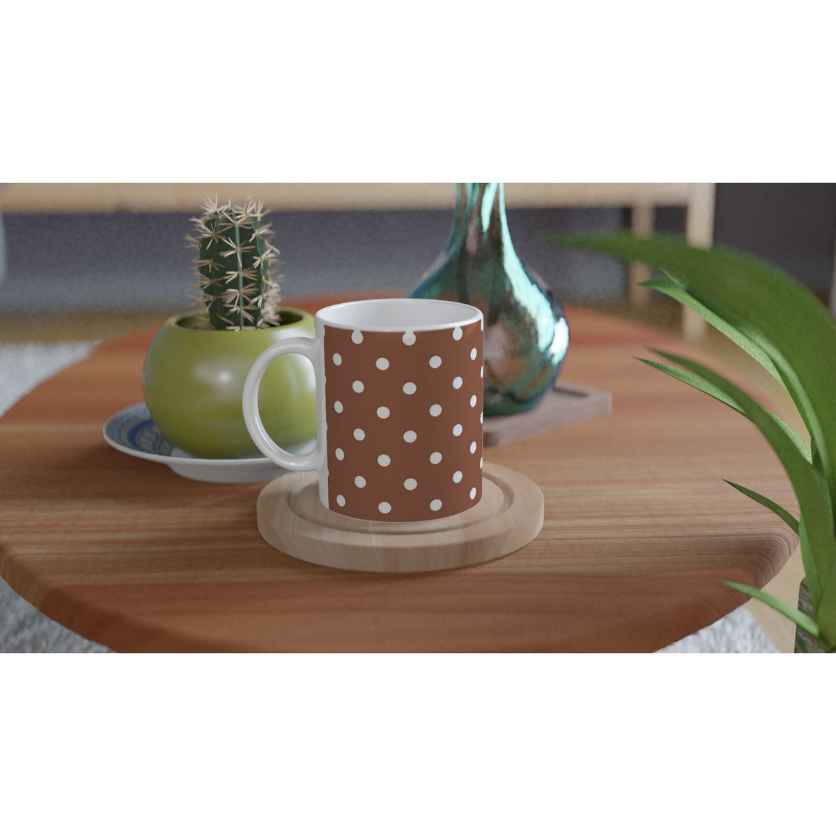 Brown and white polka dot ceramic mug on a wooden coaster beside a small cactus and teal vase.