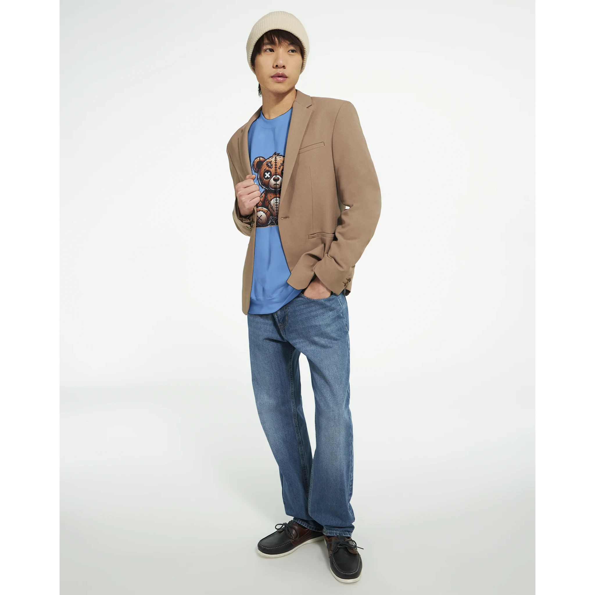 Male model in blue Stressed Teddy Bear graphic sweatshirt with tan blazer, denim jeans, beanie, and loafers.