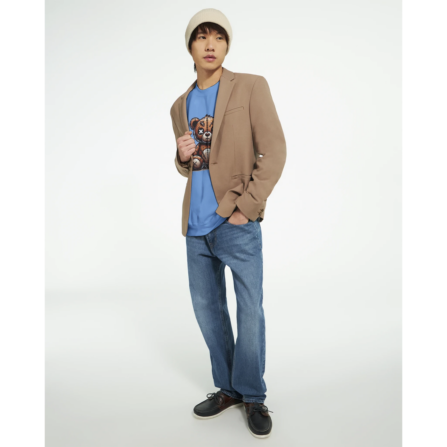Person wearing a beige blazer, blue men's graphic sweatshirt with a teddy bear design, and jeans on a white background.