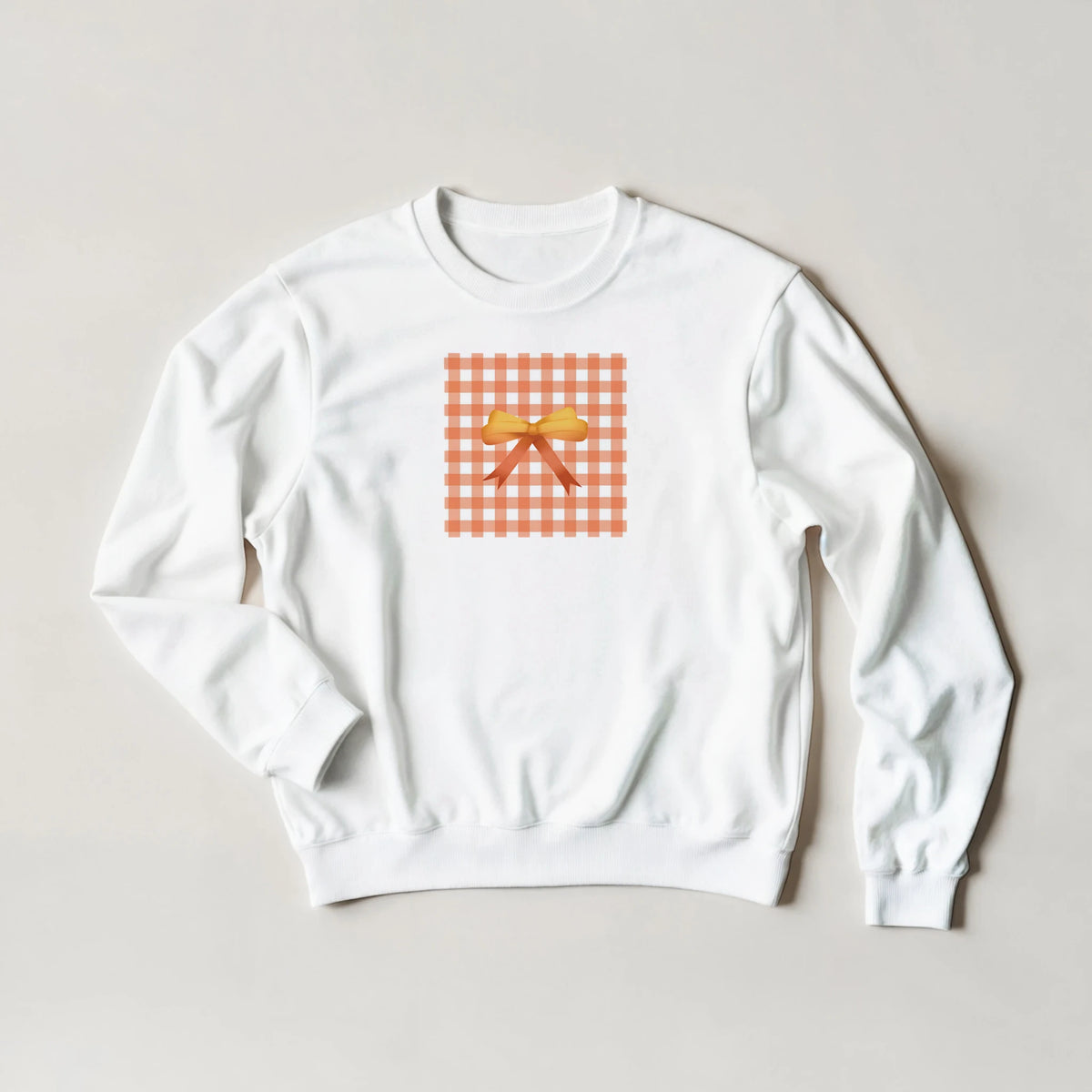 White sweatshirt featuring an orange gingham square graphic with a yellow coquette bow print.