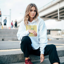 Woman wearing Retro Lemon Gingham Hoodie for Women with yellow check graphic in urban outdoor setting.
