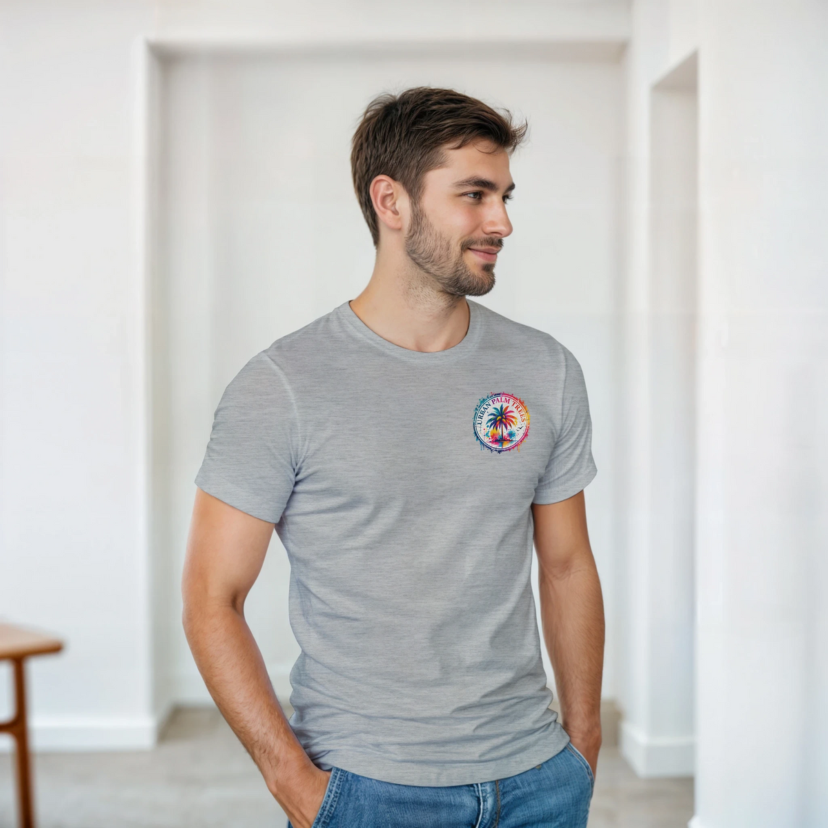 Man wearing gray t-shirt featuring colorful Urban Palm Trees circular graphic on the chest, styled with blue jeans.