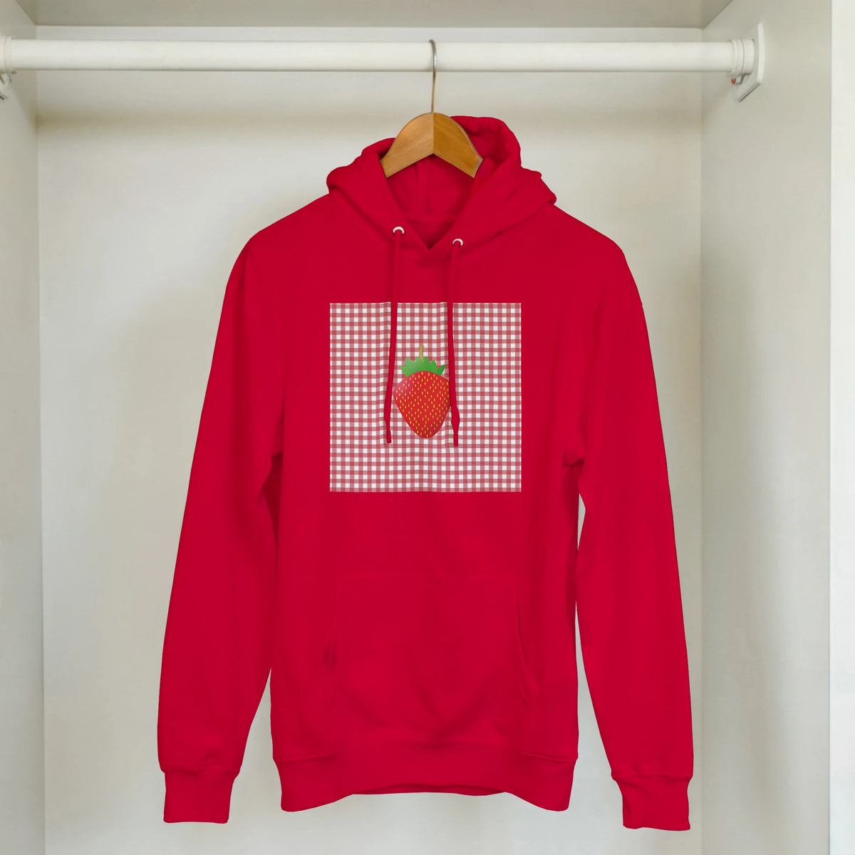 Red vintage hoodie featuring a retro strawberry graphic on a gingham square, blending nostalgia with urban style.
