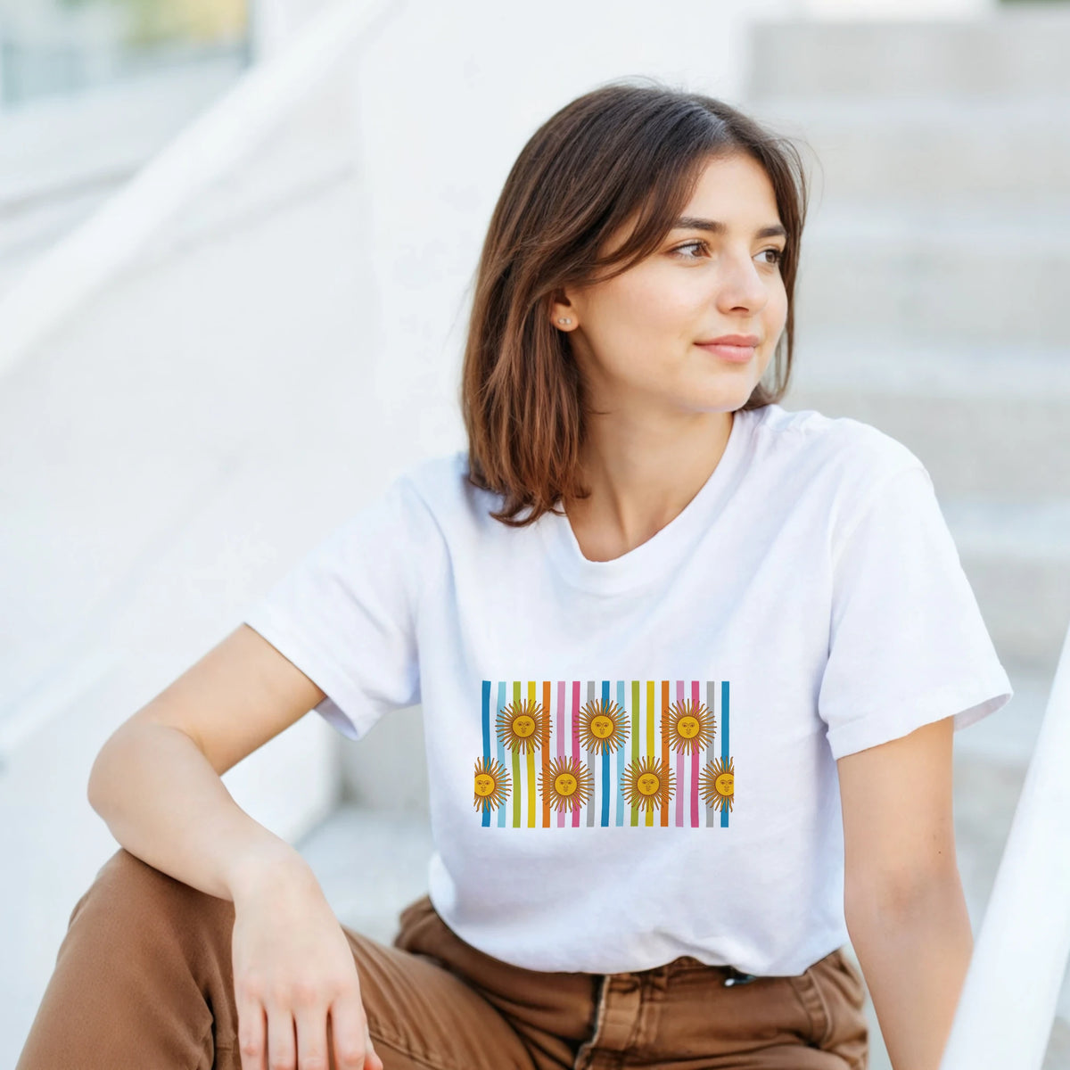 Woman in a white T-shirt with a retro rainbow sun graphic and colorful vertical stripes.