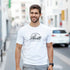 Man wearing Hustle men's graphic T-shirt in white with bold Hustle logo; soft cotton blend, streetwear vibe.