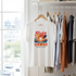 White t-shirt with 'Aloha Hawaii Paradise Island' design hanging on a rack with other shirts.