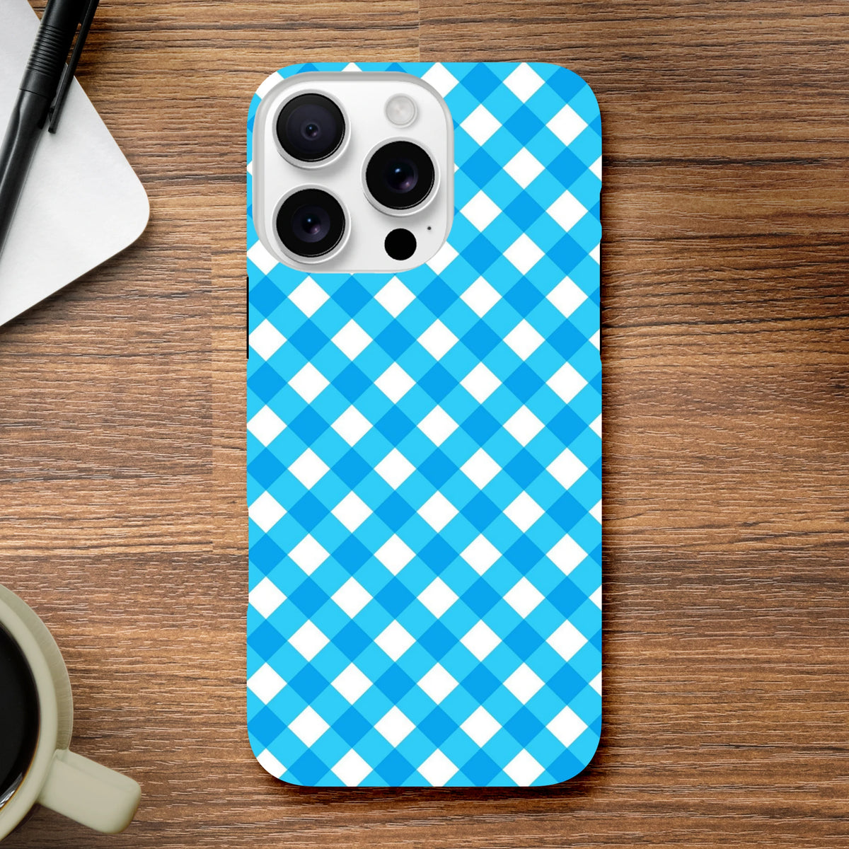 Retro blue gingham checkered tough iPhone case featuring shock-absorbing protection and wireless charging compatibility on a wooden desk.