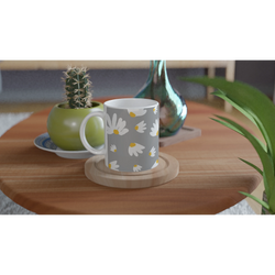Ditsy Daisy mug with white flowers and yellow centers on gray, set on a wooden table beside a cactus.