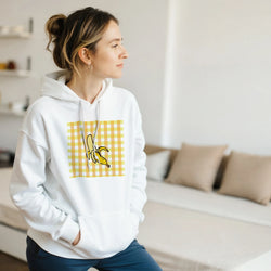 Woman wearing a white Retro Banana Gingham Hoodie for Women with a vintage yellow banana fruit graphic.