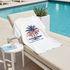 White t-shirt with 'California Los Angeles' design on a lounge chair by a pool.
