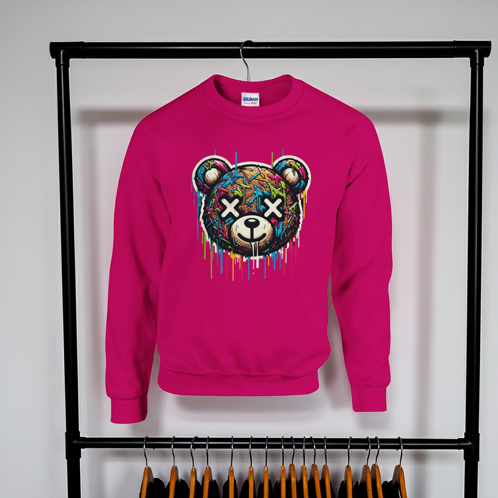 Pink sweatshirt with a colorful bear graphic on a rack against a white wall.