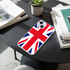 Phone case with British flag design on a black table with books and a plant.