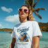 Woman wearing white Coconut Beach graphic T-shirt with tropical coconut design at a sunny beach.