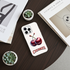 Phone case with cherry design on a wooden surface with books and plants