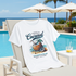 White t-shirt with coconut graphic design on a lounge chair by a poolside.