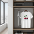White t-shirt with cherry design hanging in a wardrobe next to gray t-shirts.