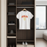 White t-shirt with 'BERLIN' print on a hanger in a wardrobe.