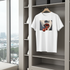 White t-shirt with graphic design hanging on a shelf with a cityscape view.