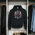 Black hoodie with a graphic design hanging in a wardrobe.