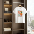 White t-shirt with pineapple graphic and text hanging in a wardrobe.