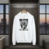 White hoodie with black graphic design on a hanger in a room with large windows.