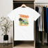 White t-shirt with 'Tropical Dreamer' design hanging in a wardrobe.