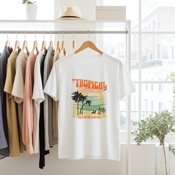 White t-shirt with 'Tropical Dreams' design hanging on a rack with other shirts.