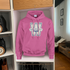 Pink hoodie with a logo hanging in a closet.