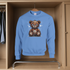 Blue sweatshirt with a teddy bear graphic hanging in a wooden wardrobe.