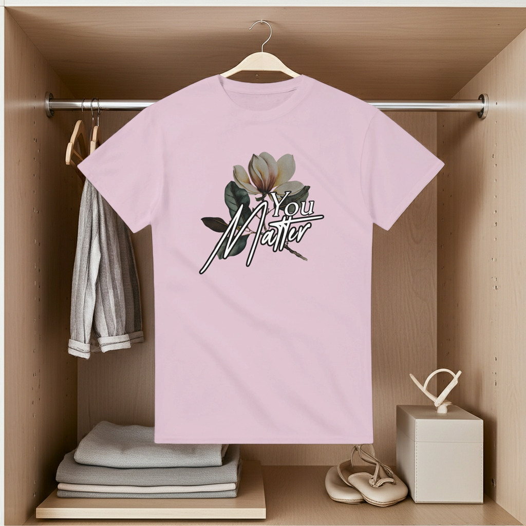 Pink t-shirt with floral design and 'You Matter' text hanging in a wooden wardrobe.