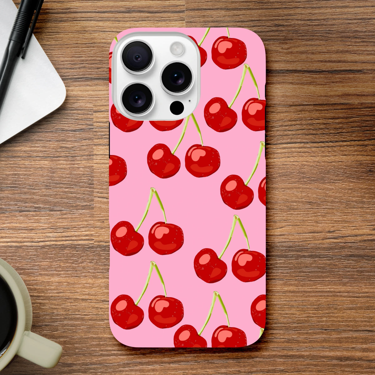 Pink iPhone case featuring a vibrant red cherry pattern on a hard pink back with triple-lens camera cutout.