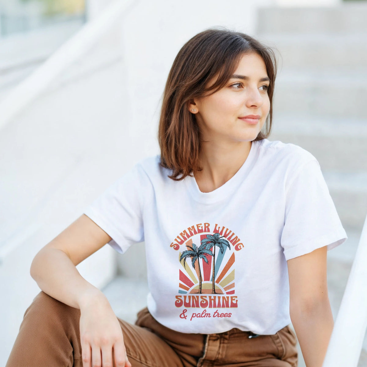 Woman wearing white cotton-blend Palm Trees graphic T-shirt with a sunset palm design in blue, pink, and orange.