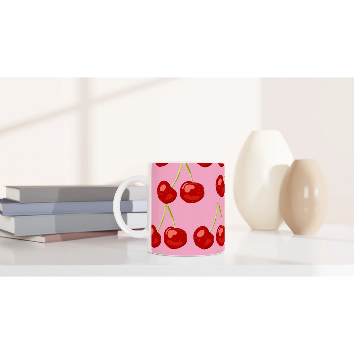 Pink cherry-print mug with white handle on a desk, a cute coquette aesthetic coffee cup.