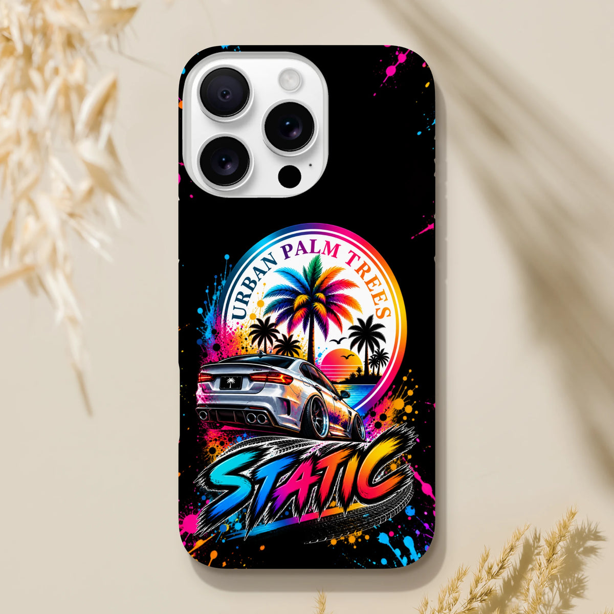 Black iPhone case featuring a silver modified car, colorful Urban Palm Trees sunset graphic, and vibrant Static splatter art.