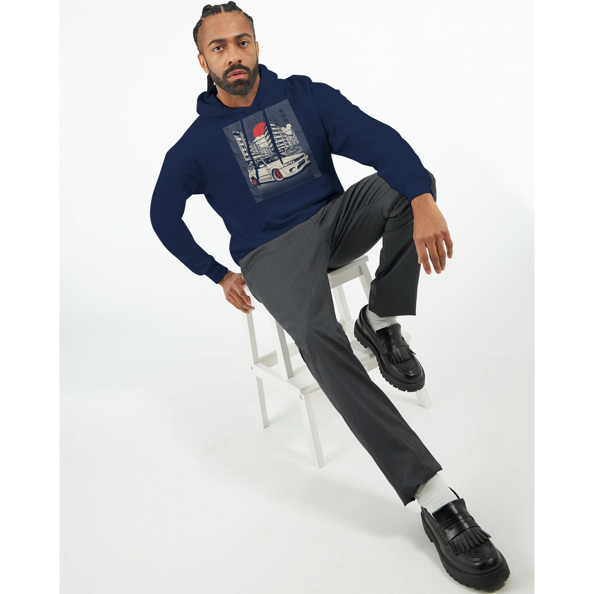 Man wearing navy Car Jumper JDM Hoodie with urban car print, seated on a stool.