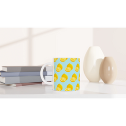 Pastel blue ceramic mug featuring a bright yellow lemon slice pattern, sitting on a white desk beside books and minimalist vases.