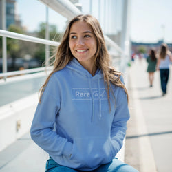 Woman in a light blue Rare Find hoodie with front pocket, outdoors near an urban railing, smiling.