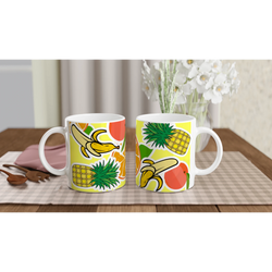 Two white ceramic mugs featuring a vibrant tropical fruit design with bananas, pineapples, and orange slices on a yellow background.
