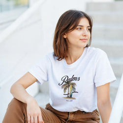 Woman in white cotton-blend Palm Tree graphic T-shirt with palm illustration, casual sunny-day look.