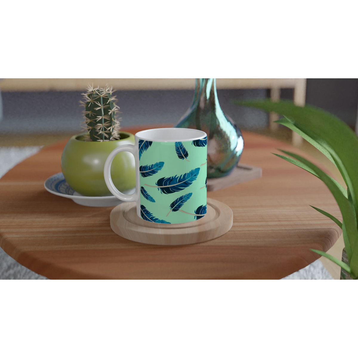 Blue Feather Mug in mint green with a blue feather pattern on a wooden table, surrounded by plants.