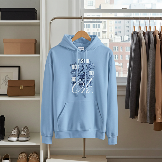 Light blue hoodie with text on a hanger in a room with shelves and clothes.