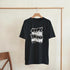 Black men's mental health graphic T-shirt with bold white 'over thinking solves nothing' text on a hanger.