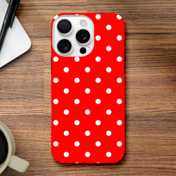 Red and white polka dot tough iPhone case for models 13-16. Cute vintage glossy cover with protective dual-layer TPU shell on wooden desk.