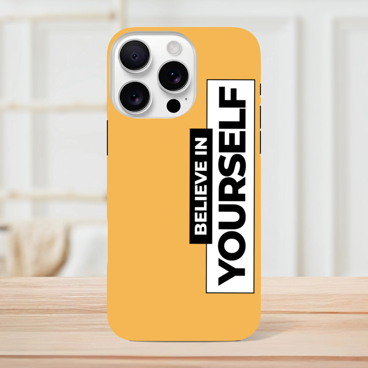 Orange tough iPhone case with high-contrast vertical "Believe In Yourself" slogan print, designed for daily carry protection.